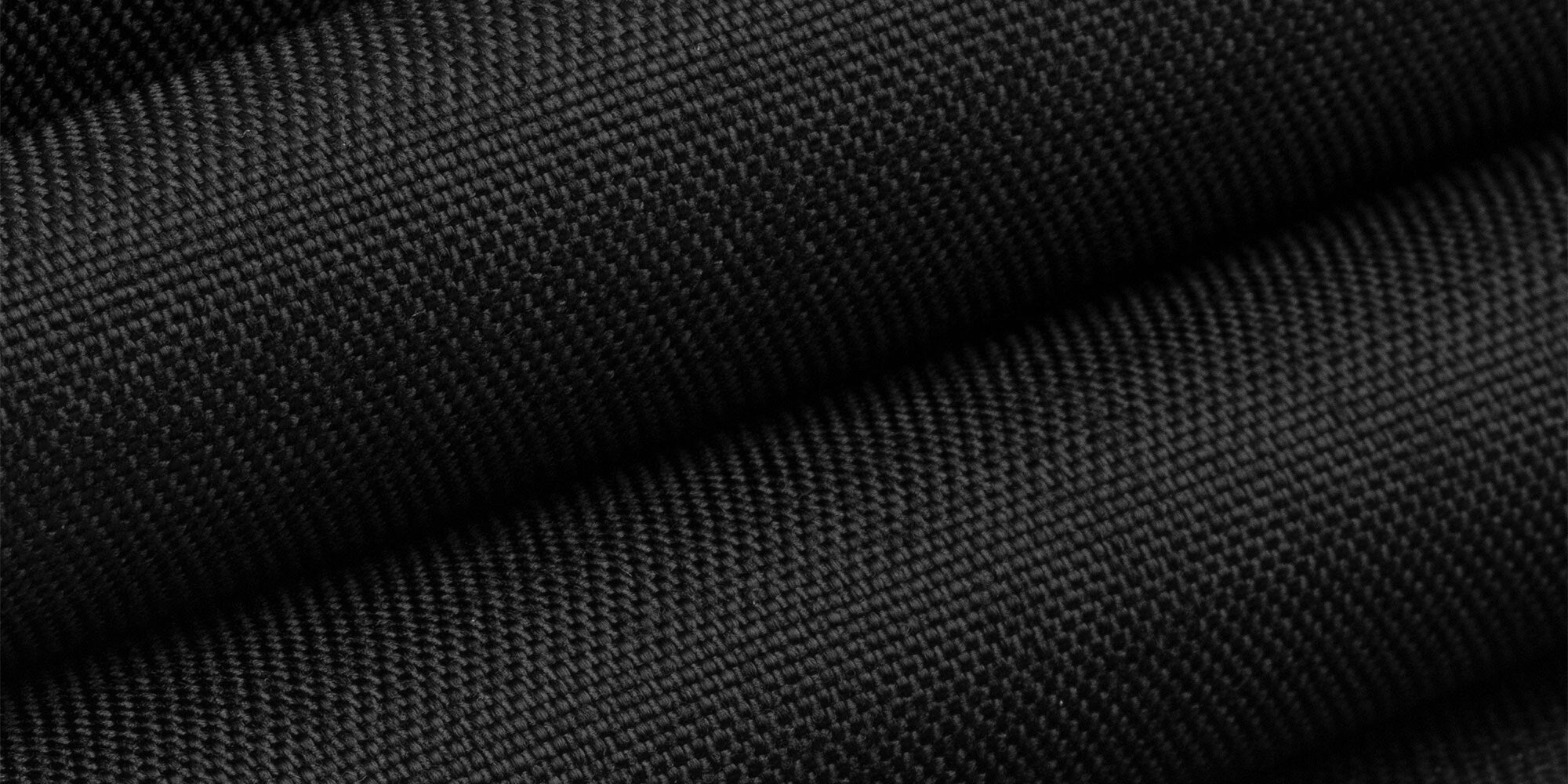 Close-up of folded, textured black fabric with a subtle diagonal pattern.