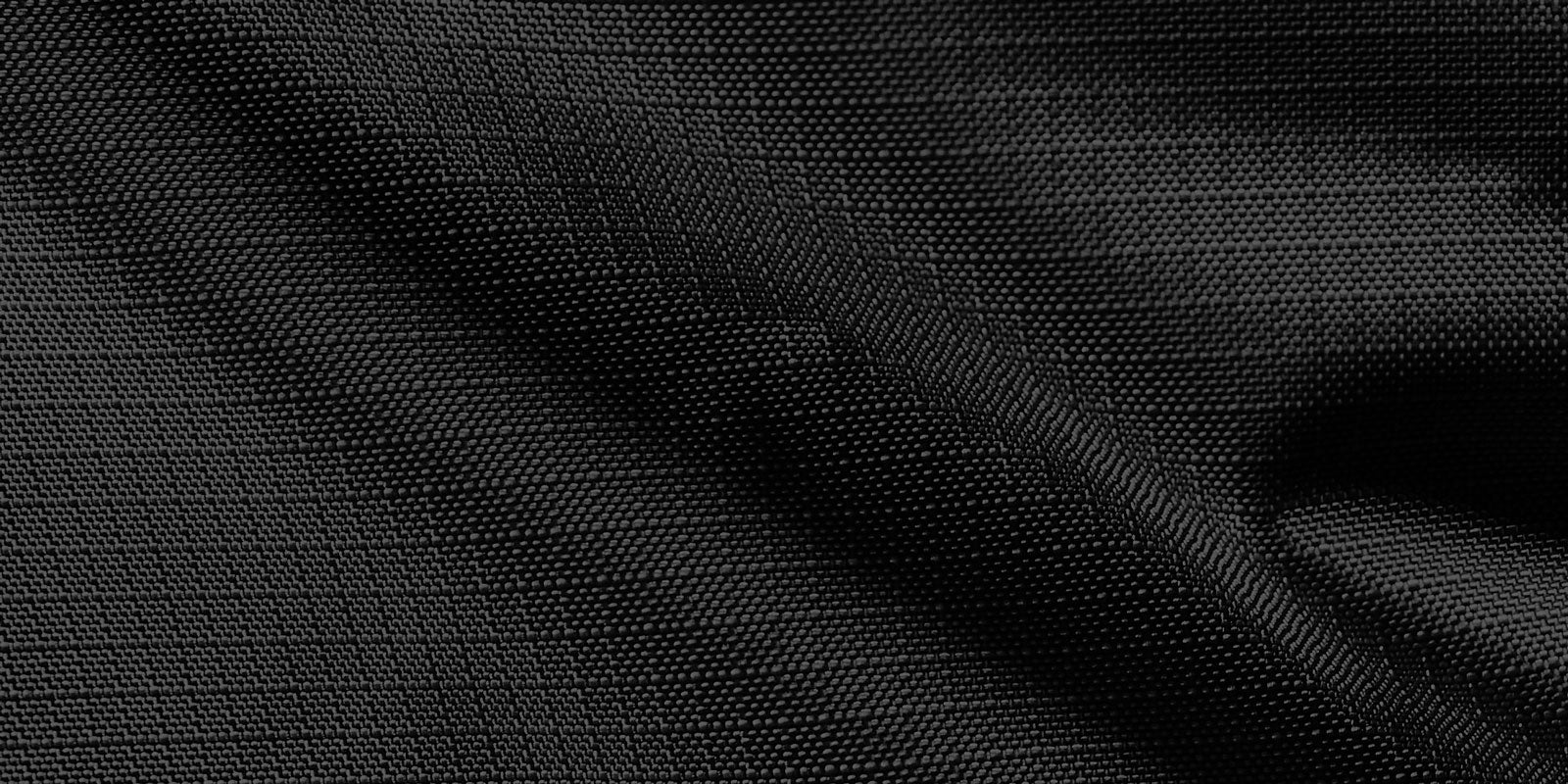 Close-up of black textured fabric with a subtle wave pattern and small dots, creating a smooth and elegant appearance.