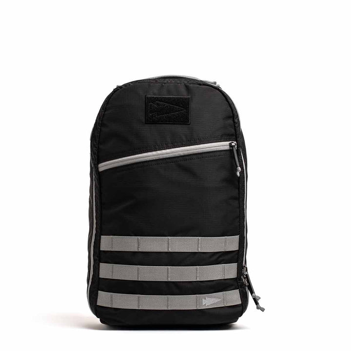 The GORUCK Bullet Ruck Laptop - Ripstop Nylon - 16L is a black backpack equipped with three gray horizontal straps, a front zippered pocket, and a dedicated laptop compartment. Crafted from water-resistant materials for enhanced durability, it also includes lumbar support for comfortable wear.