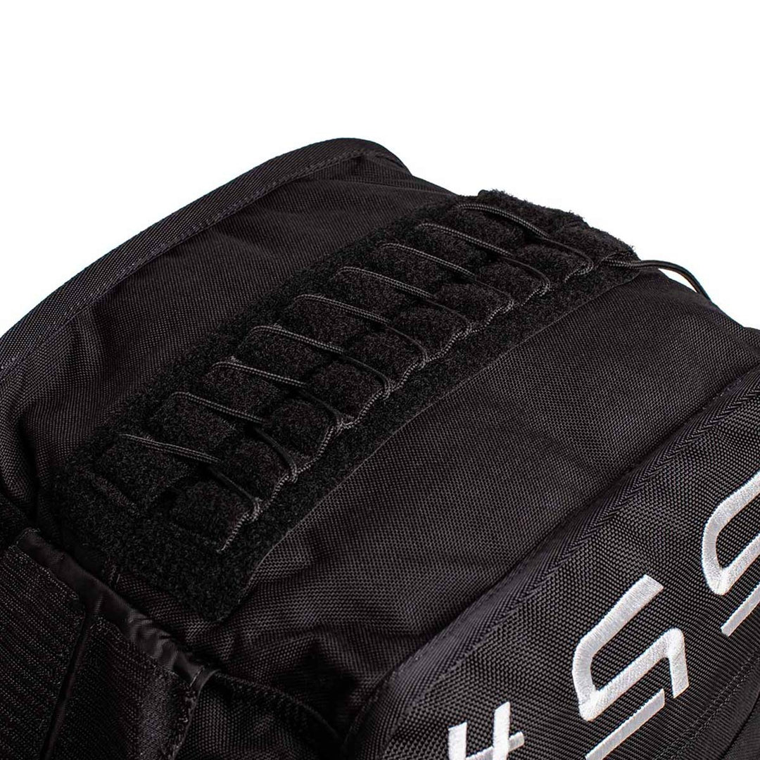 Close-up of a Sand Tombstones backpack by GORUCK, showcasing a robust multilayer closure system with open loops on the upper section and part of a white, segmented pattern on the side. The durable and textured material makes it perfect for husafell sandbag training or loaded carries.