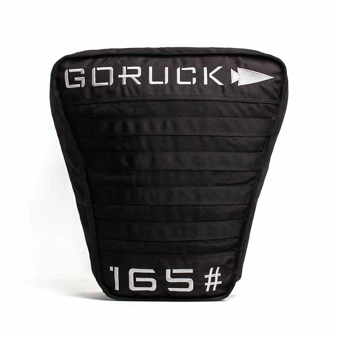 The Sand Tombstones by GORUCK is a black fitness weight plate ideal for loaded carries, featuring the GORUCK name alongside an arrow logo at the top. It weighs 165 pounds and displays a design with horizontal stitching and a robust multilayer closure system.