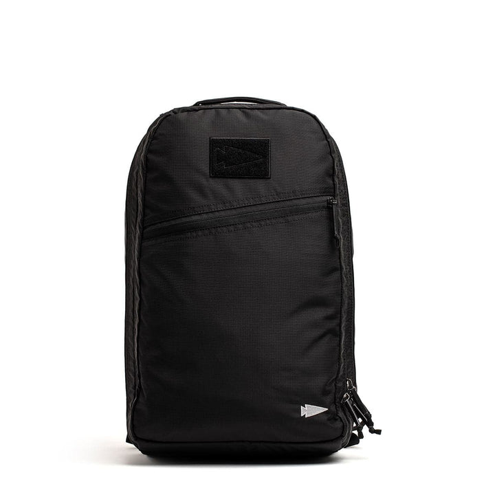 The GORUCK Bullet Ruck Double Compartment in ripstop nylon is a sleek black daypack with dual compartments, featuring a front zipper pocket and a small logo at the bottom right corner.