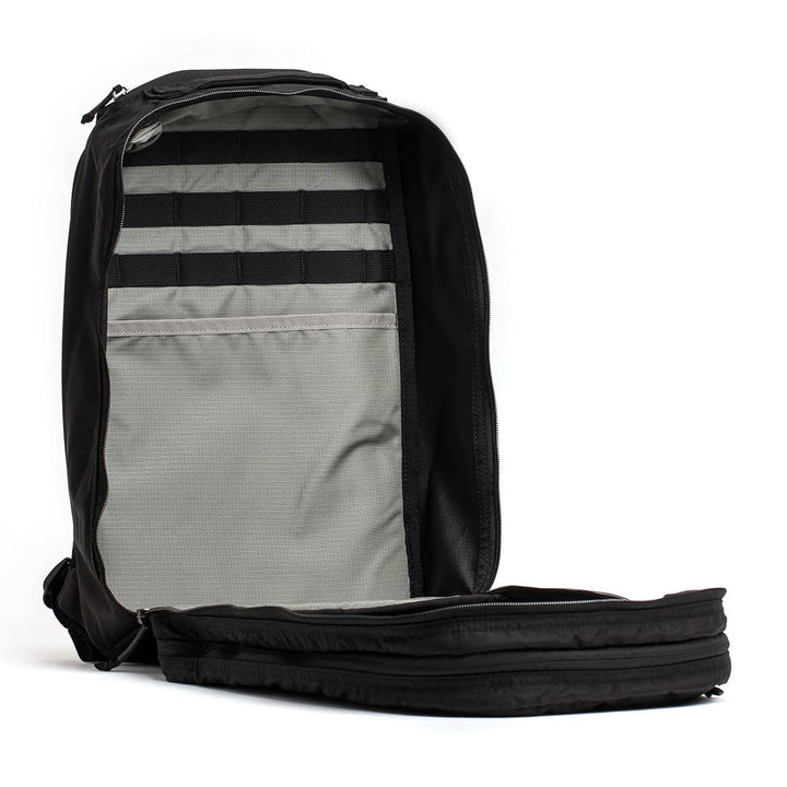 Explore the GORUCK Bullet Ruck Double Compartment, a black travel backpack crafted from ripstop nylon, featuring a gray interior with dual compartments and organizational straps for maximum efficiency.