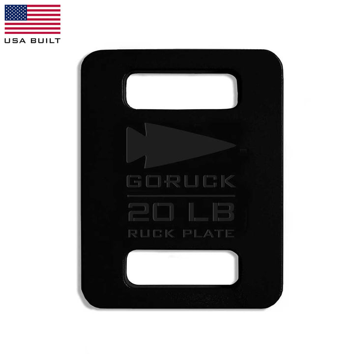 The GORUCK Ruck Plates - LB, colored in black and weighing 20 lb, are ideal for your Rucker workouts and come adorned with an arrow logo and a "USA Built" flag in the corner.