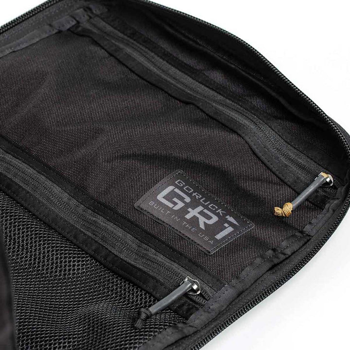 Open black rucksack with zipper pockets, featuring a "GR1 USA" label inside from GORUCK, crafted from durable 210D CORDURA.