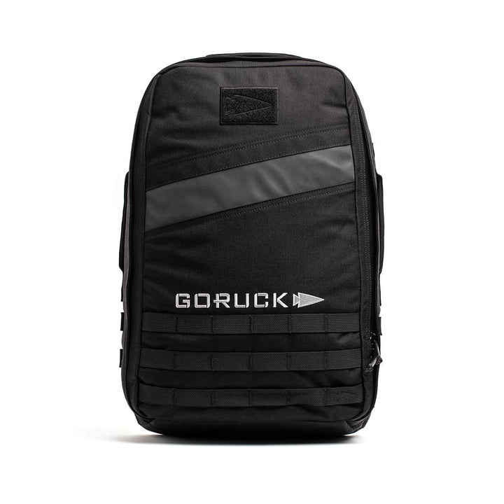 Introducing the GORUCK Rucker 4.0 backpack, designed in black with a stylish horizontal reflective stripe and prominently displaying the GORUCK logo in bold white letters. This rucksack also features MOLLE webbing at the bottom for attachments, making it an ideal companion for rucking adventures.