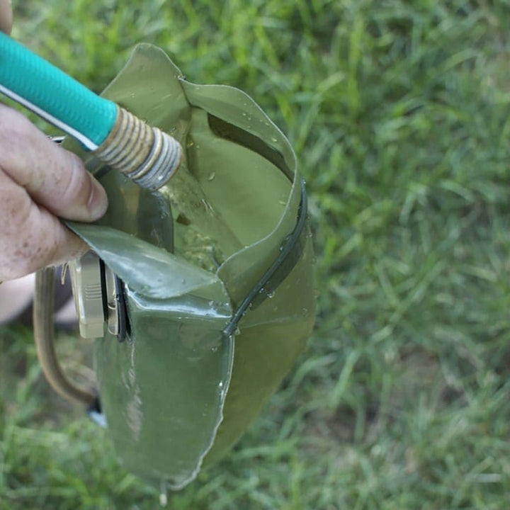 The Hydration Bladder by Source efficiently fills a water bag on the grass, embodying Special Forces-recommended hydration systems with advanced antimicrobial technology.