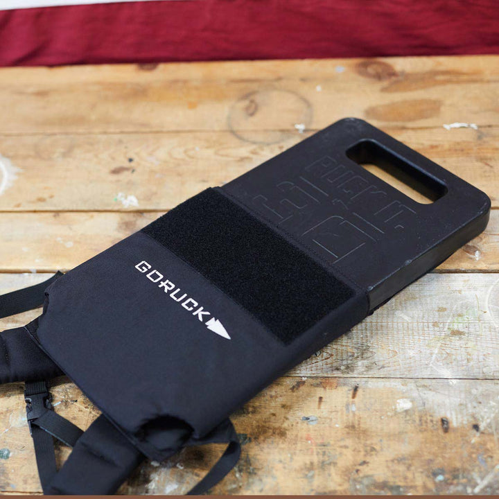 On a wooden surface, the GORUCK Ruck Plates - LB stand proudly against a backdrop of a red and white flag pattern.