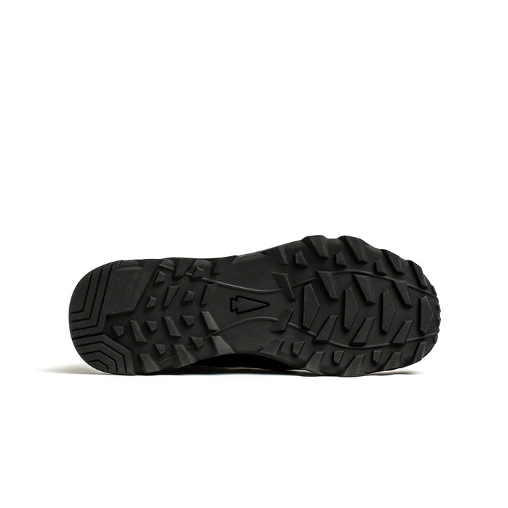 The image showcases the rugged, textured tread pattern on the black sole of GORUCK's MACV-2 Mid Top boots, designed for optimal traction. The flat sole on the ground features hexagonal and triangular shapes to enhance grip, coupled with a triple compound outsole for superior performance.