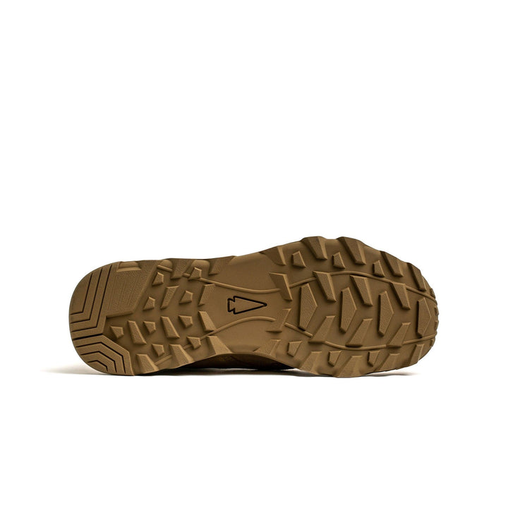 The image displays the sole of a GORUCK MACV-2 High Top in Coyote, featuring a rugged tread pattern with a small emblem at the center. The outsole's triple compound design includes angular grooves for enhanced traction.