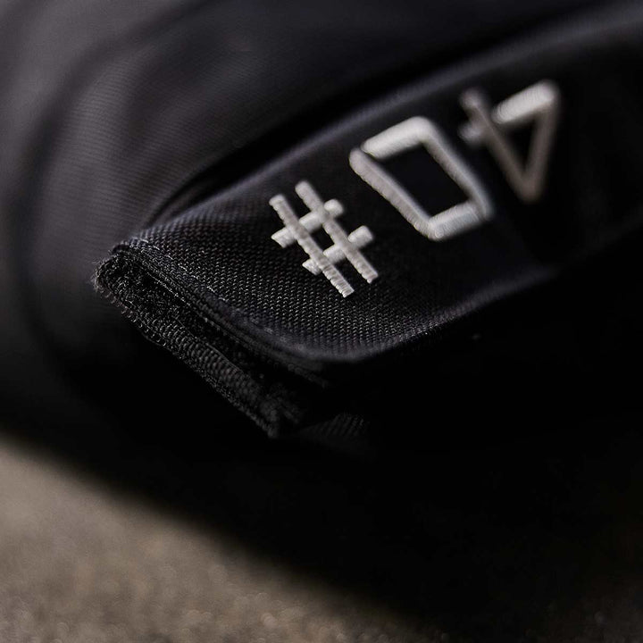 A close-up shows a black tag with white "04" stitched on it, resembling the durable texture of GORUCK Sandbag Kit (w/ Filler Bag) materials.