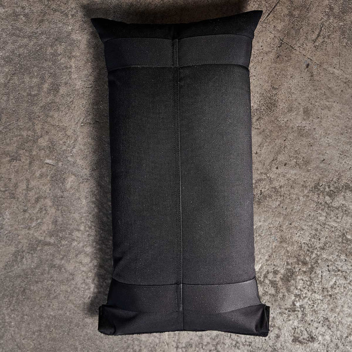 The GORUCK Sandbag Kit (w/ Filler Bag) is black and rectangular, featuring heavy-duty handles for easy maneuvering on a rough, gray concrete surface.