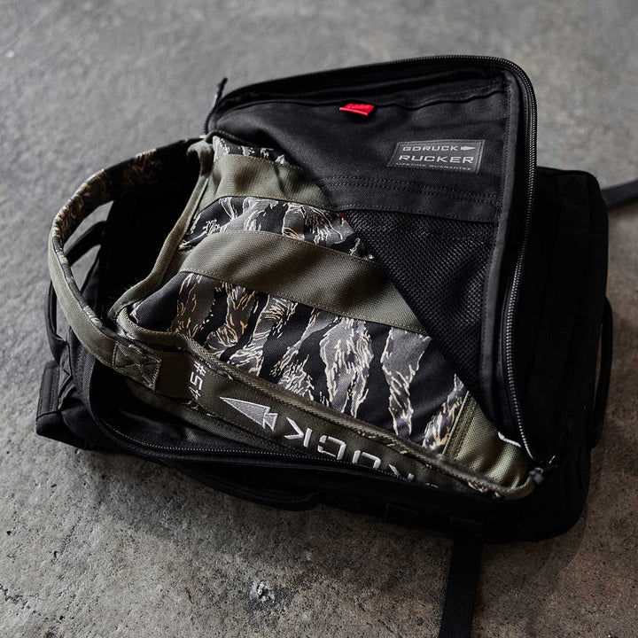 Open the Sand Jerry Can by GORUCK, crafted with Special Forces Grade materials, revealing camo-patterned contents and a visible label on the concrete floor.