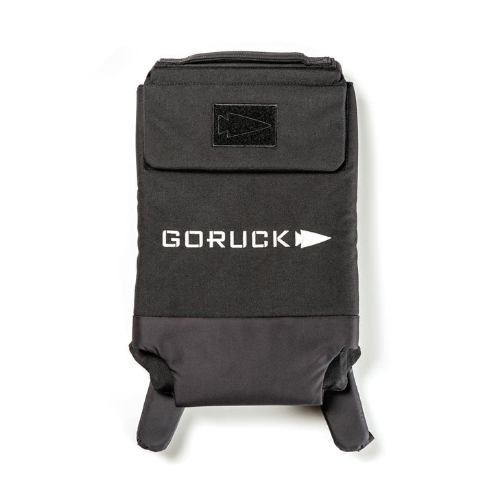 The black Ruck Plate Carrier 3.0 by GORUCK, made from durable ballistic nylon, features a compact design with a white logo. It includes a top handle and sturdy shoulder straps, along with ergonomic lumbar support for enhanced comfort.