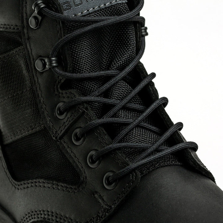 Close-up of the MACV-2 - Mid Top - Black by GORUCK, showcasing tightly laced crisscrossed black laces through metal eyelets, highlighting the texture of its leather and fabric material. The top portion features a durable triple compound outsole, visible against a white background.