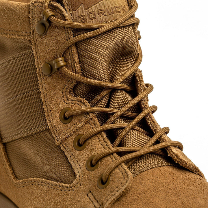 Close-up of the MACV-2 - Mid Top - Coyote boot from GORUCK showcasing its tan tactical design with detailed stitching and lacing. It features textured suede and fabric materials, metal eyelets, and a triple compound outsole for durability. The visible brand embossing enhances its rugged aesthetic.