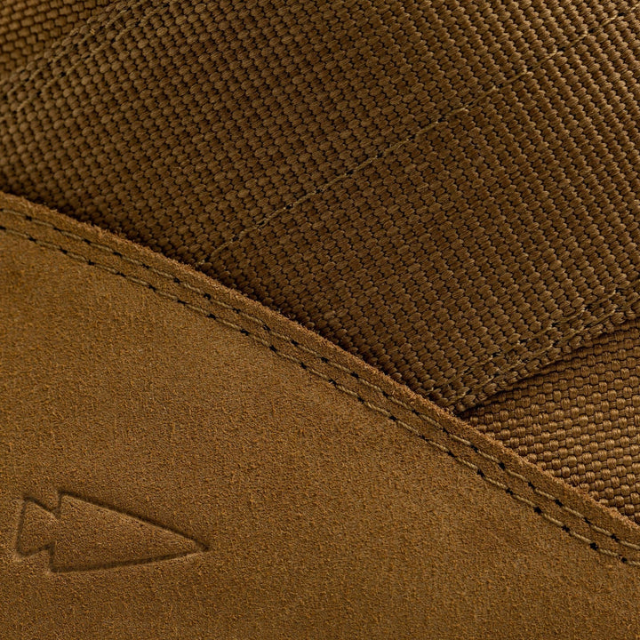 Close-up of a GORUCK MACV-2 high-top in coyote suede showing off textured fabric and visible stitching, evocative of classic jungle boots. A small embossed arrow logo on the suede adds a unique touch to its rugged style.