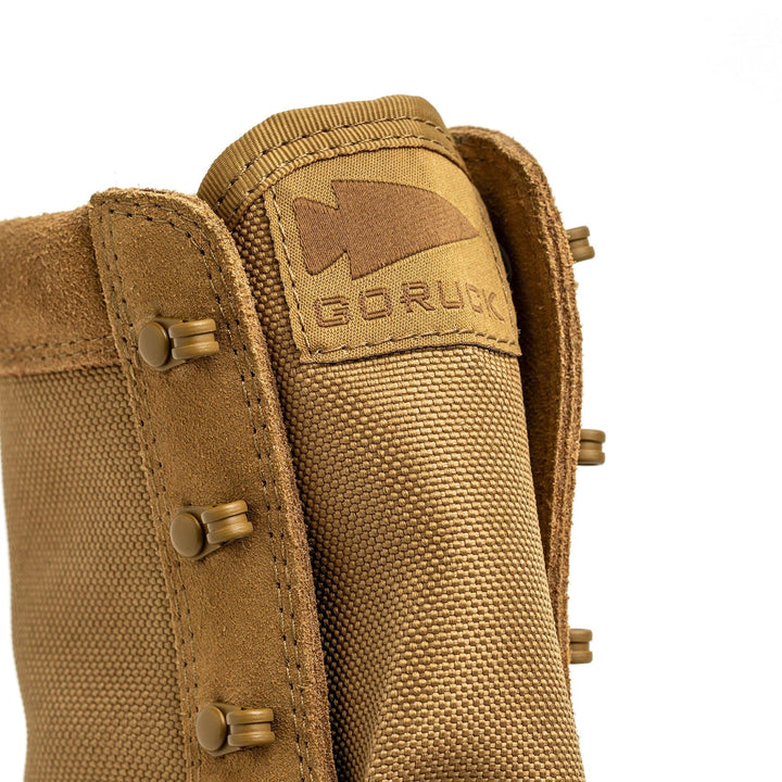 Close-up of a coyote MACV-2 High Top by GORUCK, highlighting the intricate stitching and logo label on the tongue. The boot includes metal eyelets, a sturdy triple compound outsole, and tough materials crafted to endure any challenge.