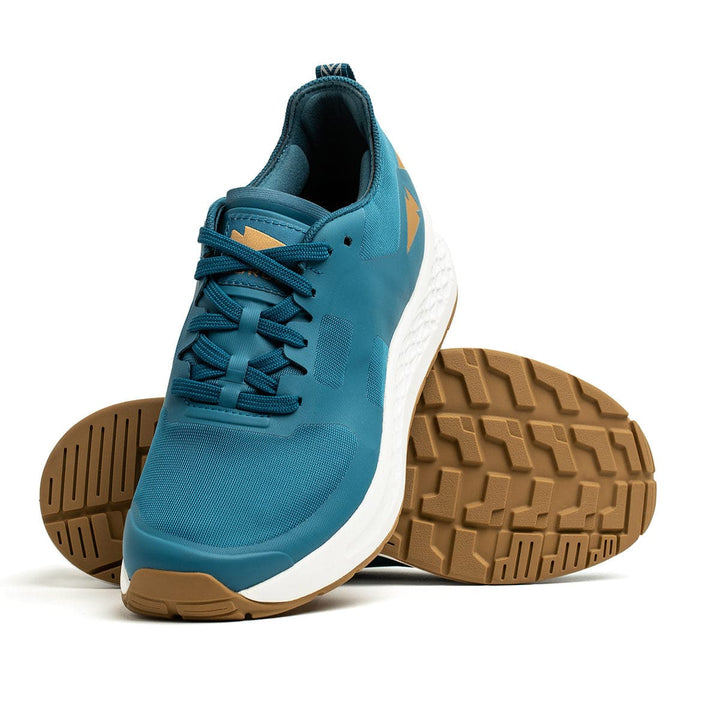 A pair of GORUCK Men's Rough Runner - Tidal Blue athletic shoes, highlighted by Gradient Density EVA white midsoles and brown textured outsoles. These high mileage shoes are laced up with the logo on the tongue and side, set against a white background with one shoe standing and the other gracefully lying on its side.