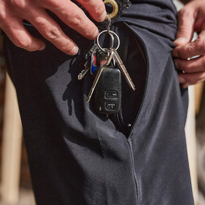 A person holds Men’s Training Shorts - ToughStretch by GORUCK, which feature a small zippered pocket revealing a set of keys attached to a car remote. The focus is on the pocket and keys, highlighting the durable ToughStretch fabric.