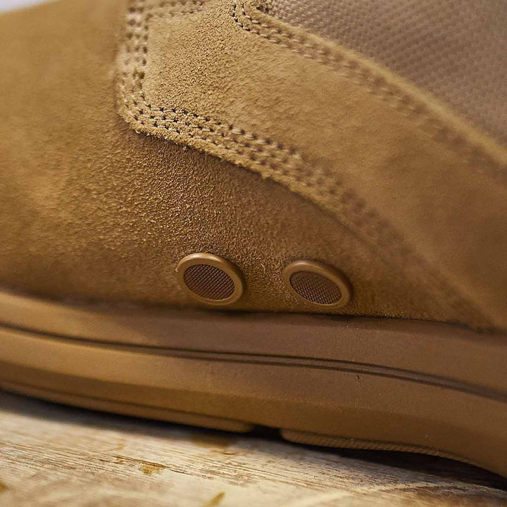 Close-up of the MACV-1 Hi-Speed - High Top by GORUCK in brown suede, featuring detailed stitching and round metal eyelets, resting on a wooden surface and highlighting its lightweight design.