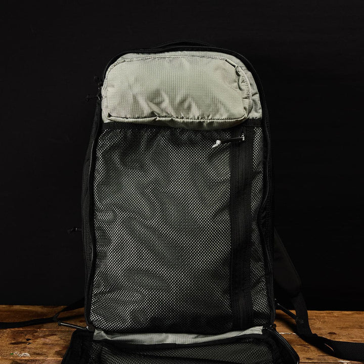 Open Bullet Ruck Double Compartment by GORUCK, in black ripstop nylon, showcasing a light gray mesh section set against a dark backdrop.