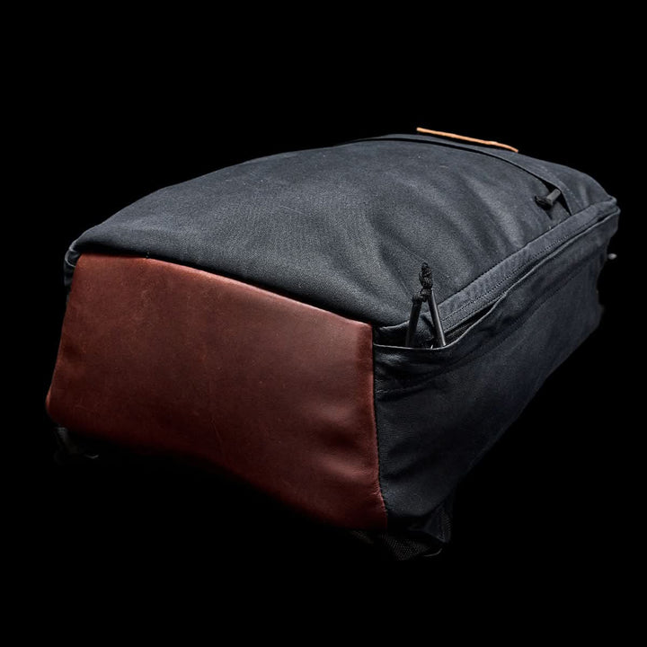 The GORUCK GR1 USA - Heritage is a black and brown rucksack made from durable waxed canvas with leather accents set against a sleek black background.