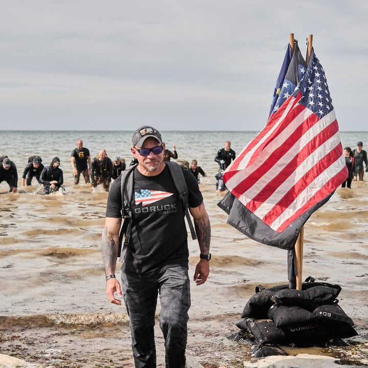 Triumphantly leading the group out of the water, each member proudly wears a GORUCK Performance TAC Hat - TOUGHDRY. As U.S. flags wave and sandbags line the shore, the sweat-wicking technology keeps everyone comfortable and prepared for any adventure that lies ahead.