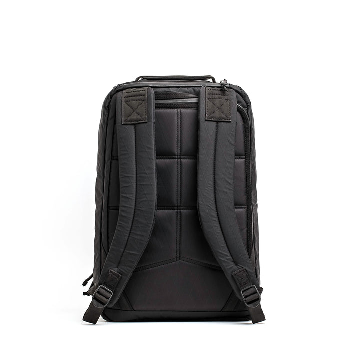 The GORUCK GR1 USA - X-PAC is a black backpack with padded shoulder straps, a quilted back panel, and AquaGuard zippers for weather protection, shown on a white background.