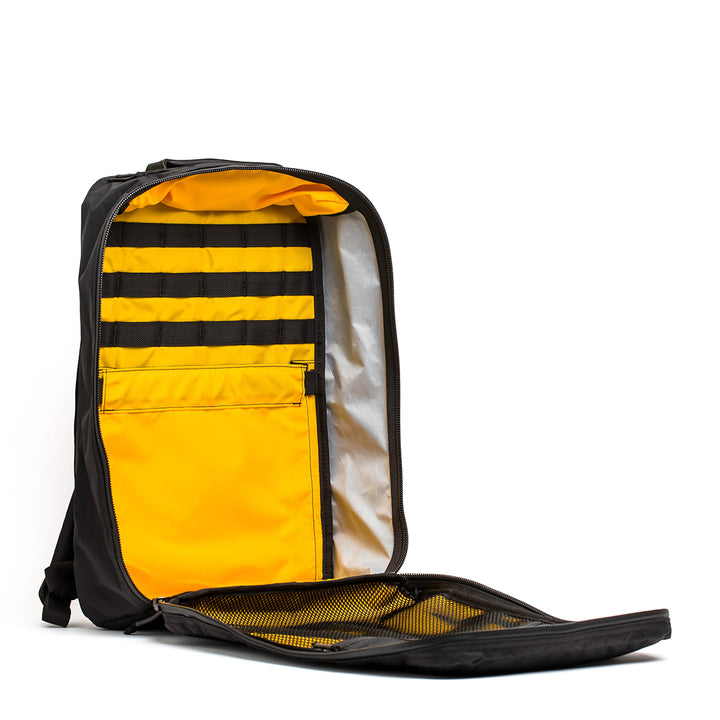 The GR1 USA - X-PAC by GORUCK in black and yellow is open, displaying interior compartments and a mesh pocket, all secured with AquaGuard zippers for enhanced waterproof protection.