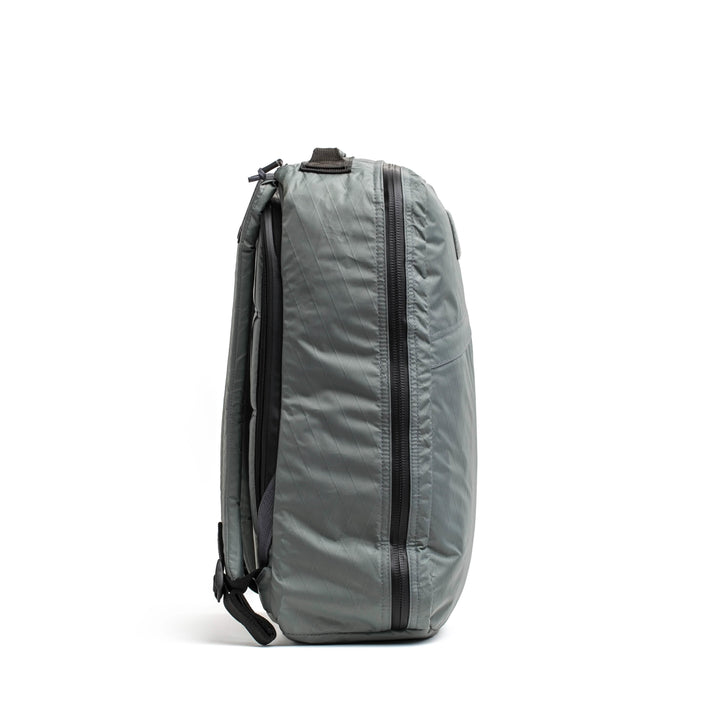 The GORUCK GR1 USA - X-PAC backpack, in gray, with AquaGuard zippers on the side and crafted from durable X-PAC material, is shown standing upright against a white background.