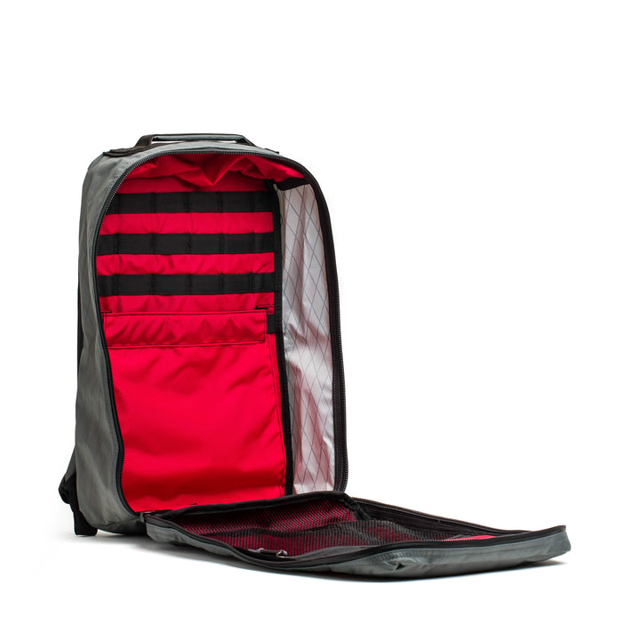 The GR1 USA - X-PAC by GORUCK boasts a sleek black exterior with a vibrant red interior, offering various compartments and straps. Crafted with X-PAC fabric and AquaGuard zippers, it ensures durability and keeps essentials organized and waterproof.