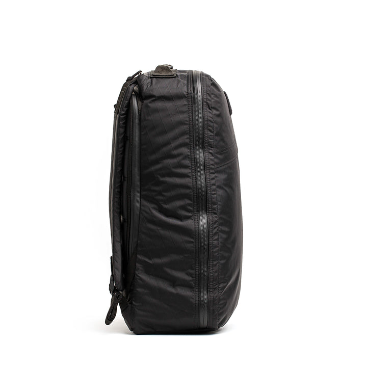 The GORUCK GR1 USA - X-PAC backpack, shown from the side against a white background, features a sleek design with AquaGuard zippers for enhanced waterproof protection.