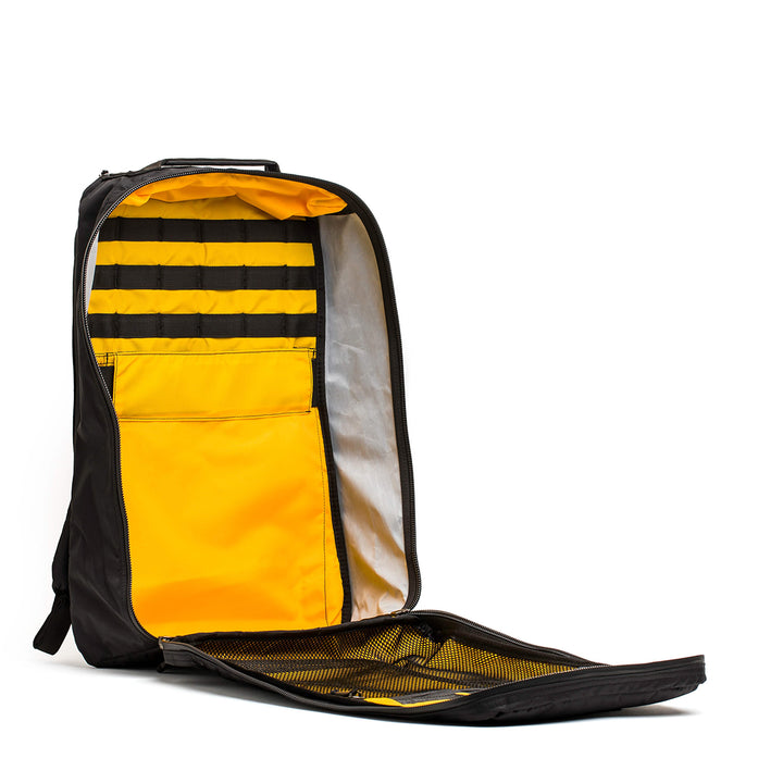 The GORUCK GR1 USA - X-PAC black backpack, with a yellow interior, showcases AquaGuard zippers and waterproof X-PAC material. It is opened to reveal its compartments and mesh pockets against a white background.