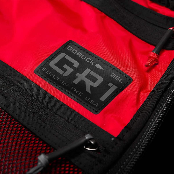 Black and red fabric backpack showcasing AquaGuard zippers and a close-up of the label "GORUCK GR1 USA - X-PAC 26L Built in the USA.