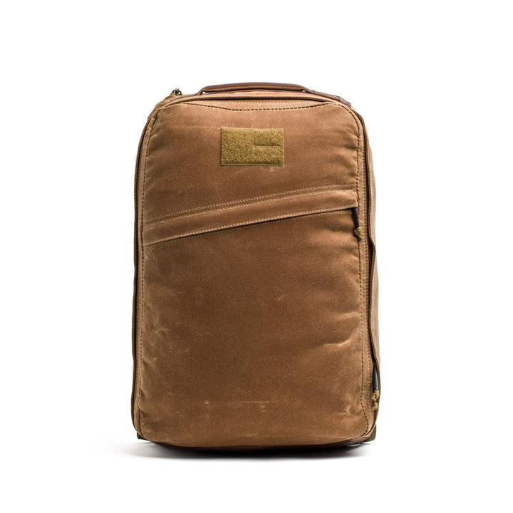 The GR1 USA - Heritage backpack from GORUCK, made of brown waxed canvas, stands upright against a spotless white background.