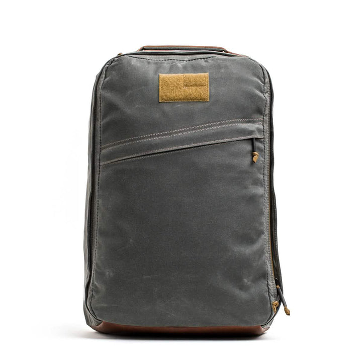 The GORUCK GR1 USA - Heritage is a stylish, gray waxed duck canvas backpack featuring brown details, a front zipper pocket, and a durable design. Perfect for any adventure with its timeless functionality.