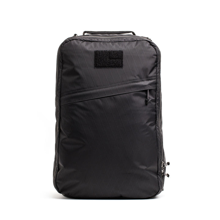 The GORUCK GR1 USA - X-PAC is a black backpack with a sleek, waterproof design, AquaGuard zippers, a front zipper pocket, and a top handle, shown isolated on a white background.