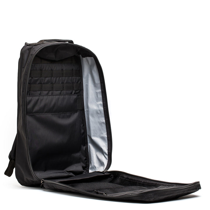 The GR1 USA - X-PAC by GORUCK is an open black backpack with AquaGuard zippers, highlighting its compartments and light gray interior against a white background.