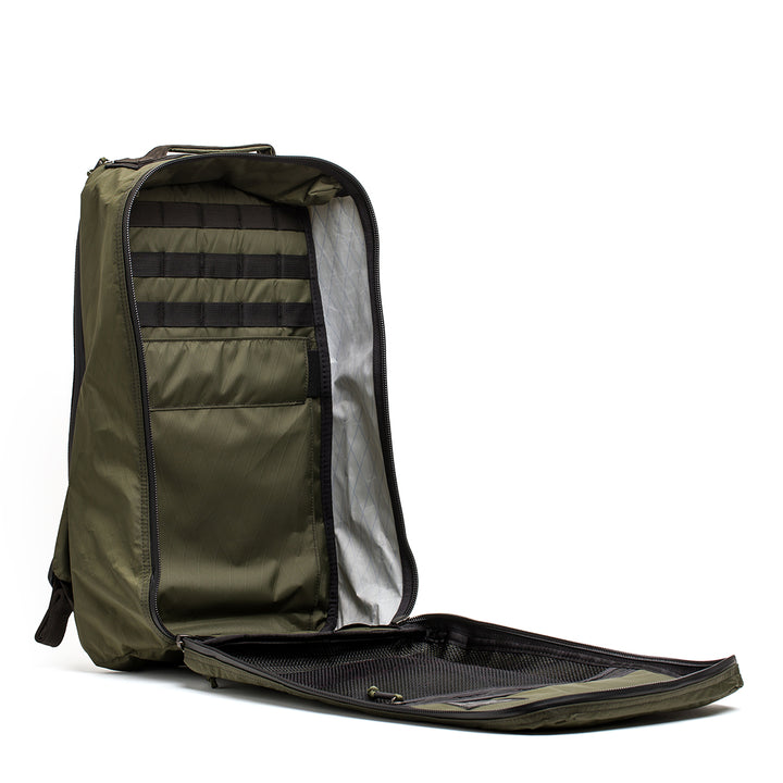 The GR1 USA - X-PAC by GORUCK is an open green backpack equipped with AquaGuard zippers, multiple compartments, and a zippered mesh pocket.