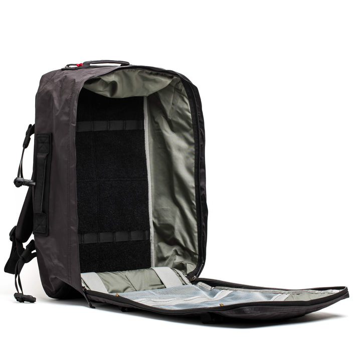 The GR3 - Dyneema backpack by GORUCK is showcased against a white background, highlighting its sleek black design. Unzipped, it reveals a spacious light gray interior with multiple compartments and mesh pockets. The adjustable straps are visible on the side.