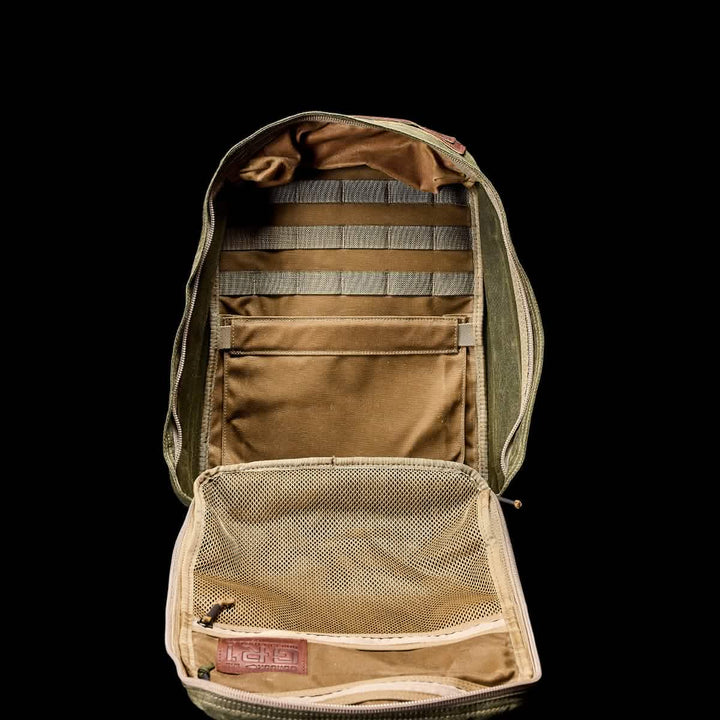 The GR1 USA - Heritage by GORUCK is an open olive green backpack with compartments and a mesh pocket, crafted from waxed duck canvas, shown on a black background.