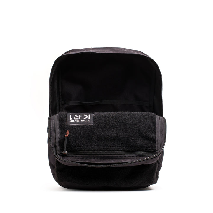 GORUCK's KR1 2.0 - Kid Ruck is a black backpack designed for kids, featuring reinforced stitching, an open main compartment, and a visible front pocket against a white background.