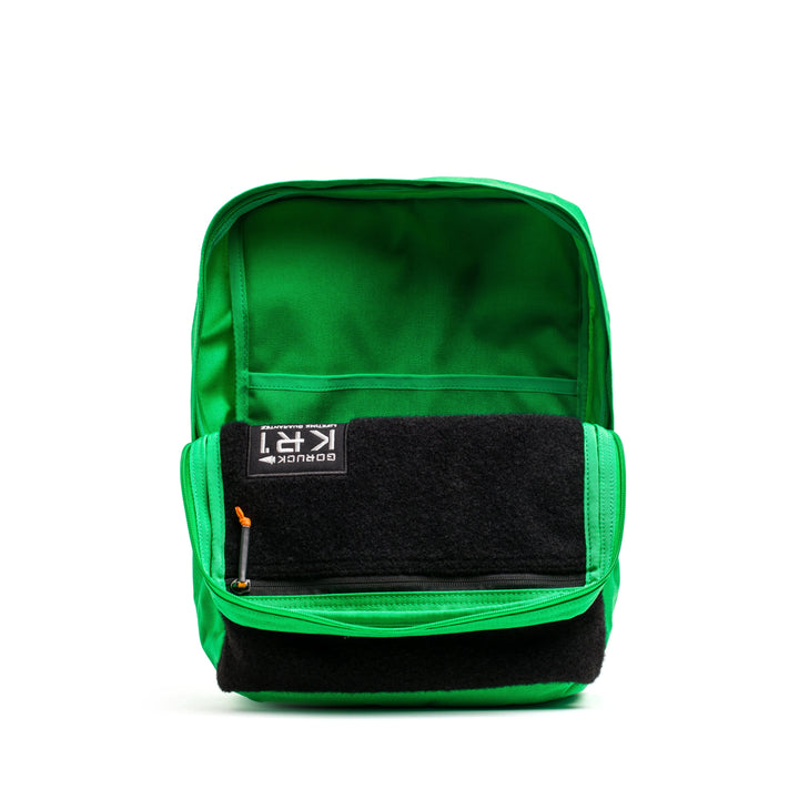 The GORUCK KR1 2.0 - Kid Ruck, featuring a vibrant green exterior and black interior with multiple compartments, is shown standing upright against a white background. Its reinforced stitching highlights the backpack's durability.