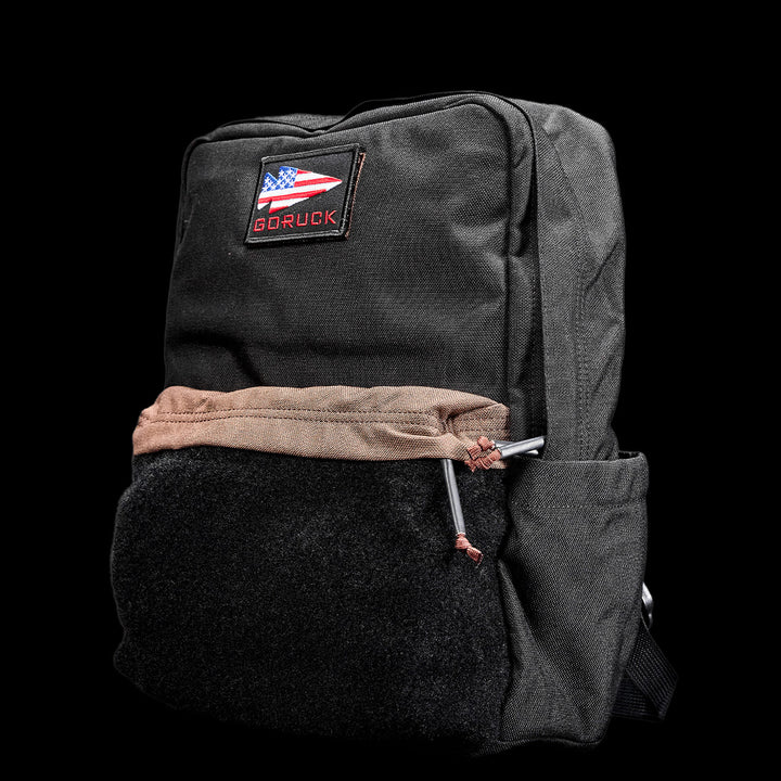 GORUCK's KR1 2.0 - Kid Ruck is a black kids backpack with reinforced stitching, showcasing an American flag patch and the "GORUCK" branding against a sleek black backdrop.