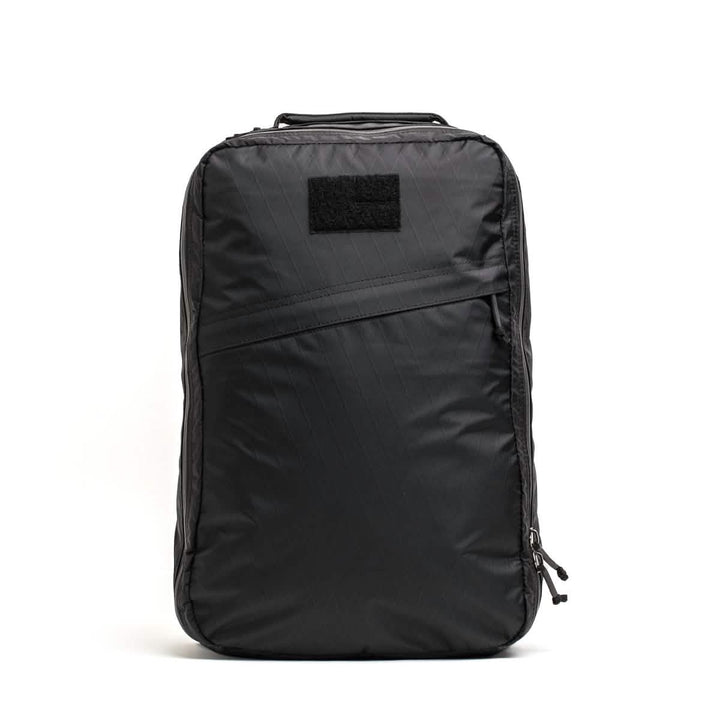 The GR1 USA - X-PAC by GORUCK is a black rectangular backpack made from durable X-PAC material, featuring AquaGuard zippers, a front zipper pocket, and a top handle, photographed against a white background.