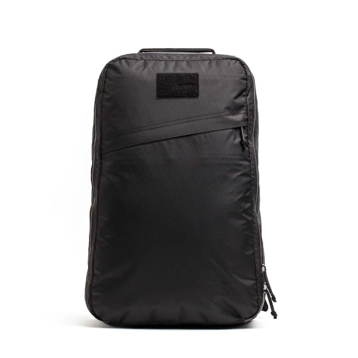 The GR1 USA - X-PAC by GORUCK is a sleek black backpack with a minimalist design, crafted from waterproof X-PAC fabric and featuring AquaGuard zippers, displayed against a plain white background.