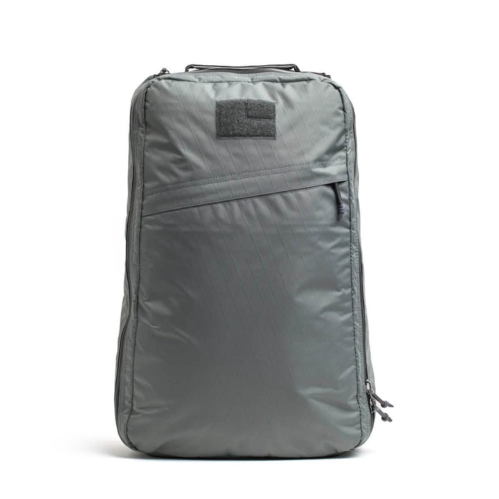 The GR1 USA - X-PAC backpack by GORUCK is shown in gray with an angled AquaGuard zipper pocket and a top handle, set against a plain white background.