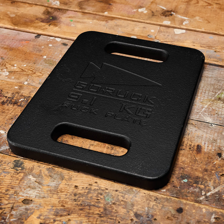 A GORUCK Ruck Plate with handles sits on a worn wooden surface.