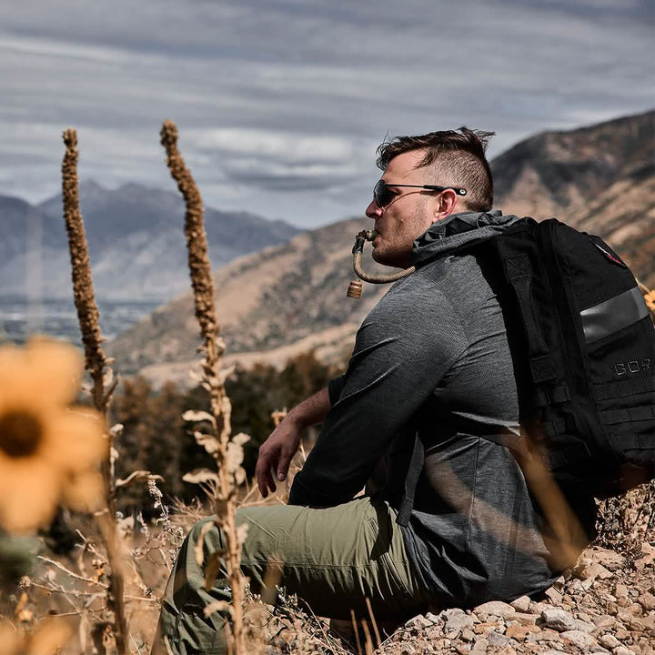 A man relaxes on a hilltop, enjoying the view while sitting with his rucksack